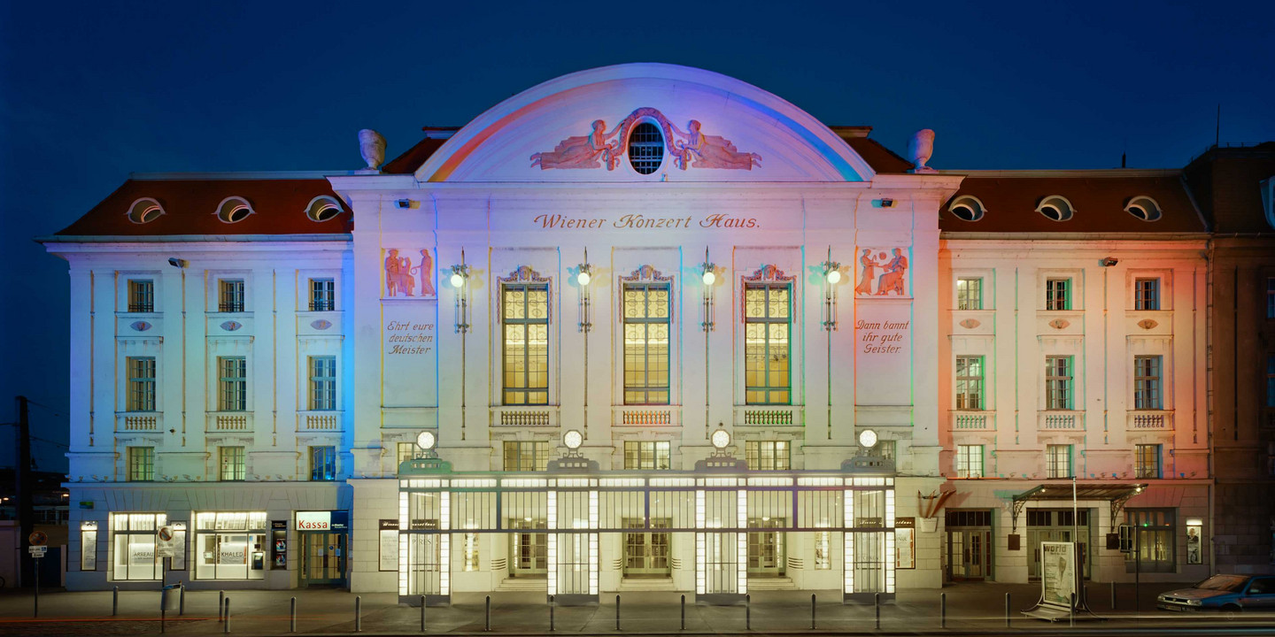 Wiener Konzerthaus © Rupert Steiner Historisches Theatergebäude bei Nacht mit bunter Beleuchtung in Blau, Weiß und Rot.