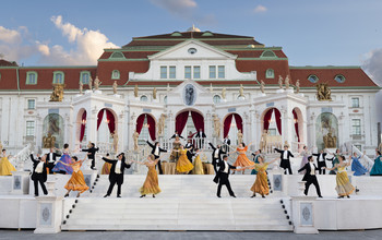 © Anna Stöcher Tanzpaare in festlicher Garderobe vor barocker Schlosskulisse bei Open-Air-Veranstaltung.