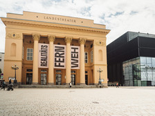 Klassizistische Fassade des Tiroler Landestheaters mit modernem Anbau und großem Vorplatz