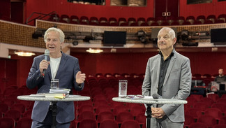 Pressekonferenz im Burgtheater mit zwei Sprechern vor rotem Zuschauerraum