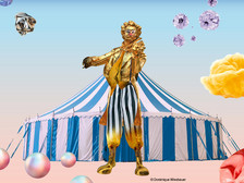 Farbenfrohes Zirkusmotiv mit Statue von Johann Strauss vor blau-weißem Zelt und fantasievollen Elementen