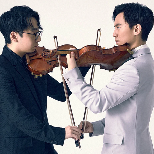 © August Man Zwei Geiger stehen sich gegenüber und spielen Violinen, deren Bögen sich in der Mitte kreuzen.