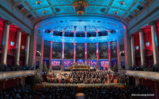 © Ludwig Schedl Ein festlich beleuchteter Konzertsaal mit Orchester, Chor und Dirigenten auf der Bühne. Im Hintergrund prangen große Orgelpfeifen, die Decke ist blau-rot ausgeleuchtet, und mehrere Weihnachtsbäume schmücken die Bühne. Das Publikum verfolgt das Konzert von den Rängen und dem Parkett aus.