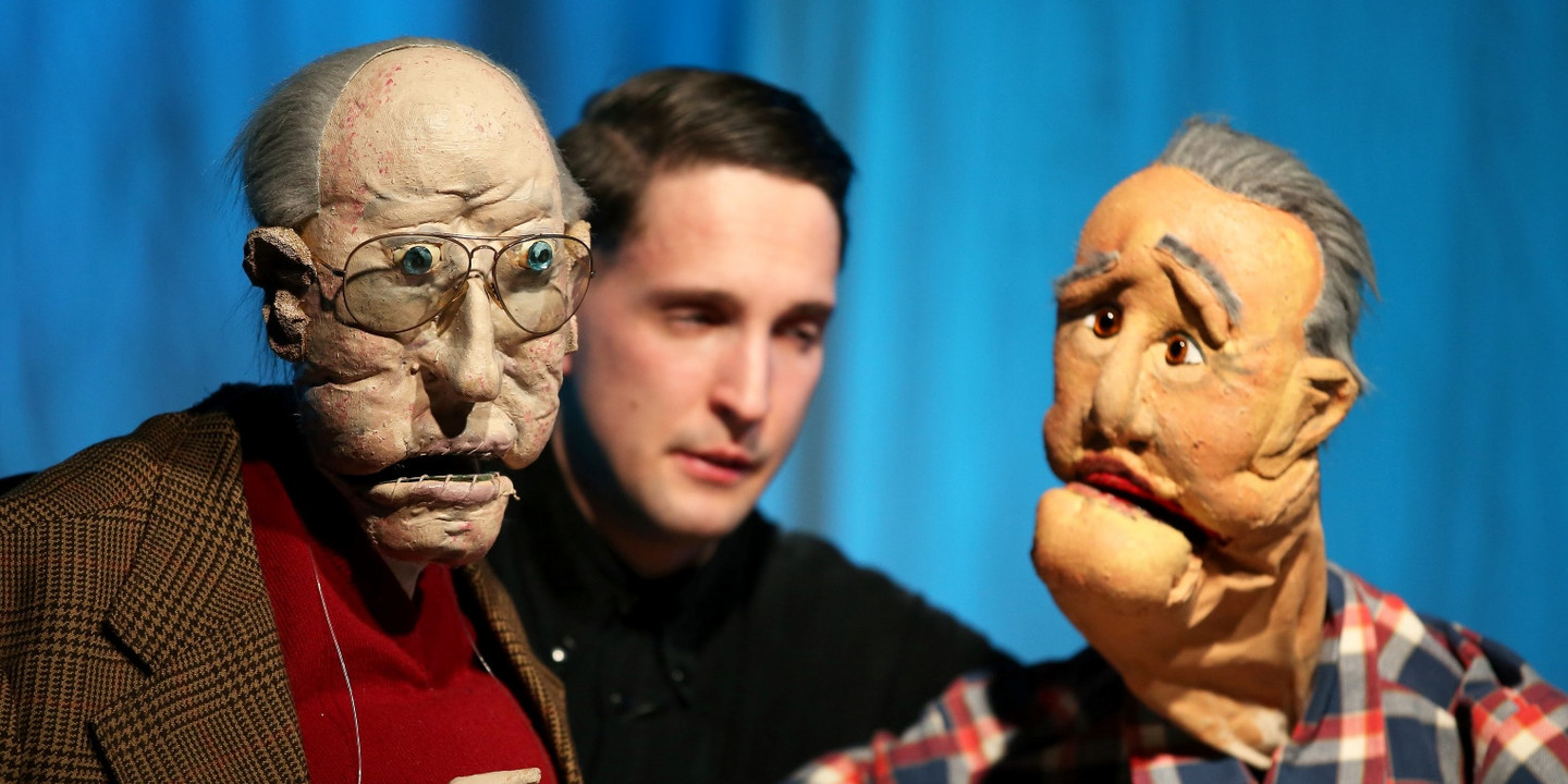 © Barbara Palffy Puppenspieler mit zwei lebensechten Handpuppen auf der Bühne, die ältere Männer darstellen.