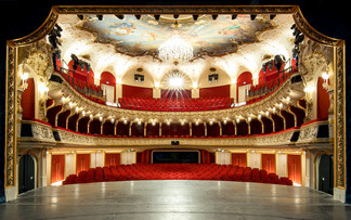 © Neumayr/Christian Leopold Blick von der Bühne in den prachtvollen Zuschauerraum eines Theaters mit rotem Samt, goldenen Verzierungen, Kronleuchter und Deckenmalerei. Die Sitzreihen sind leer, die Architektur wirkt historisch und opulent.